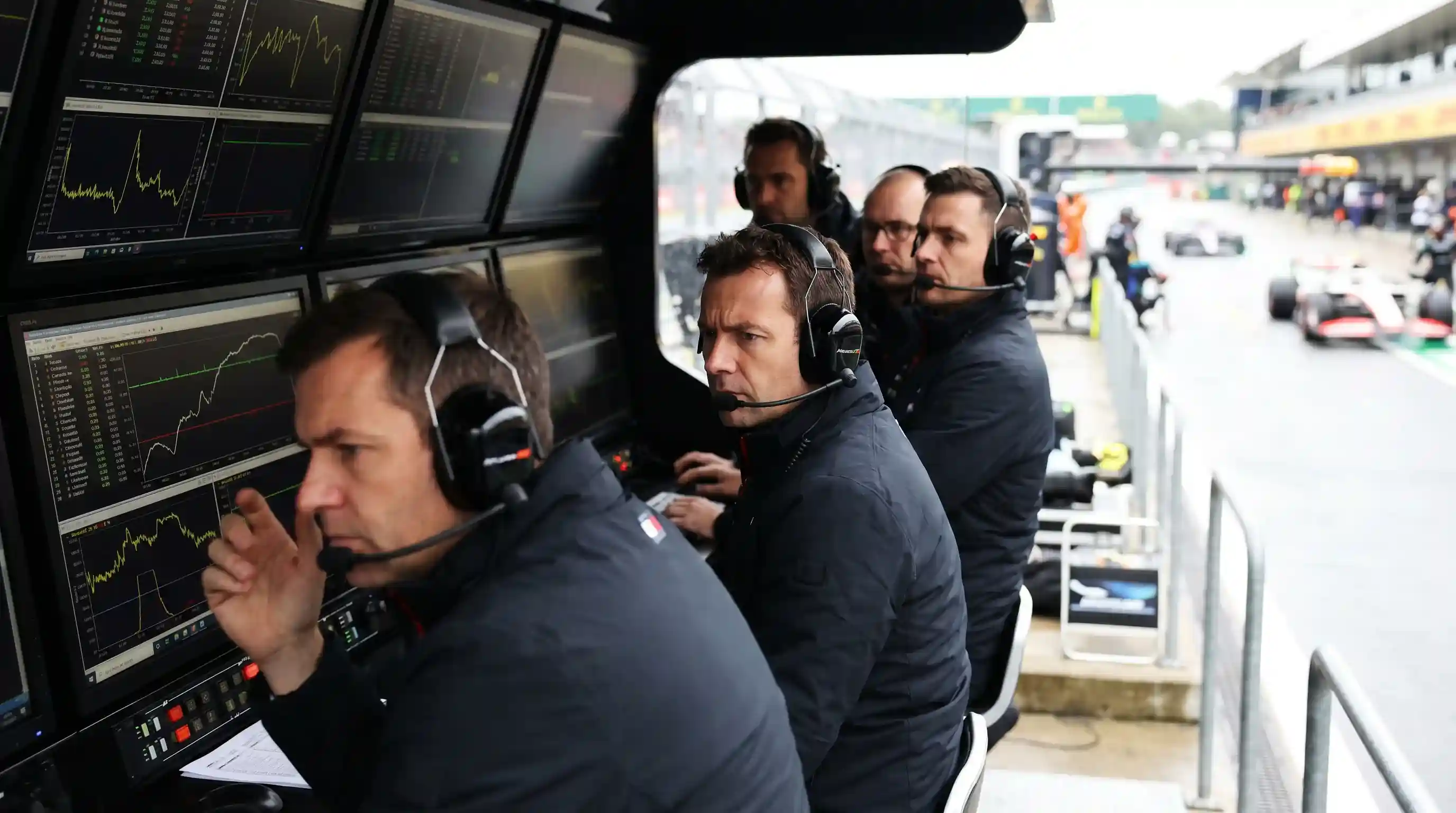 Инженери на F1 отбор анализират данни на pit wall